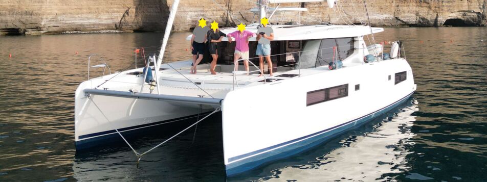 Katamaran Leopard 45 „Lady Mara“ ankert mit Crew an Deck vor einer Steilküste – Yachtcharter Mallorca