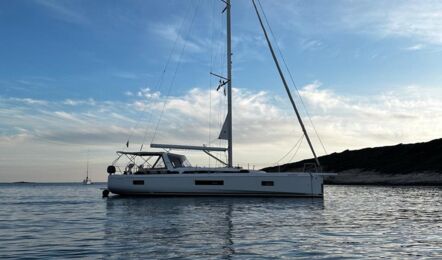 Steuerbordansicht der Segelyacht Oceanis 51.1.3 „Marny“ vor Anker in einer Bucht mit abendlicher Atmosphäre – Yachtcharter Kroatien