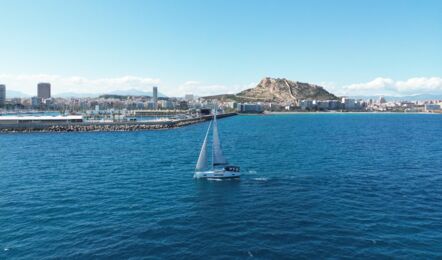 Heckansicht der Segelyacht Hanse 460 „Antares“ unter Segeln vor einer Stadtkulisse mit Burgberg – Yachtcharter Mallorca