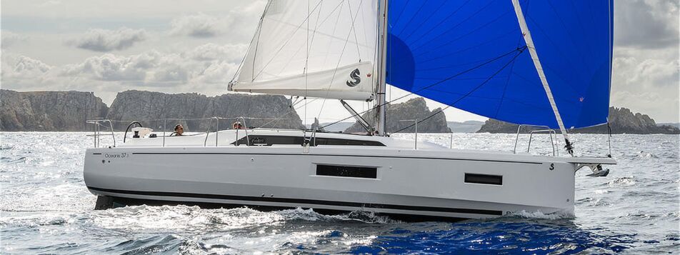 Steuerbordansicht einer Oceanis 37.1 unter Segeln entlang einer Küste mit Klippen im Hintergrund (Werftbild) – Yachtcharter Ostsee