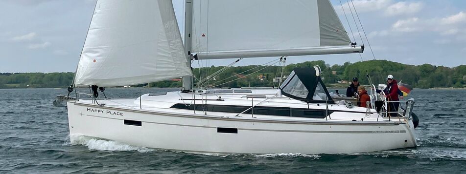 Seitenansicht der Segelyacht Bavaria cruiser 37 „Happy Place“ unter Vollzeug mit Crew auf der Förde – Yachtcharter Ostsee