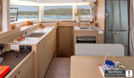 Heller Salon einer Lagoon 38 mit hellem Holzausbau, offener Pantry, großem Kühlschrank und Blick nach Steuerbord (Werftbild) – Yachtcharter Mallorca