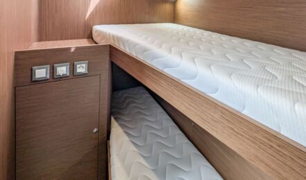 Kabine der Segelyacht Oceanis 51.1 „Aquaris“ mit zwei übereinander angeordneten Einzelkojen und Rumpffenster – Yachtcharter Mallorca