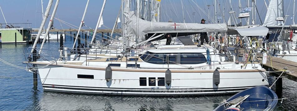 Seitenansicht der Segelyacht Sirius 35DS „Baltic Bö" am Steg in Barth mit Sprayhood und Beiboot – Yachtcharter Ostsee