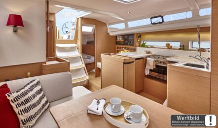 Heller Salon einer Sun Odyssey 440 mit hellem Holzausbau, offener Pantry und Blick nach achtern (Werftbild) – Yachtcharter Kroatien