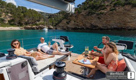 Crew entspannt im Cockpit einer Sun Odyssey 455 mit erweiterter Liegefläche vor Anker in einer felsigen Bucht (Werftbild) – Yachtcharter Kroatien
