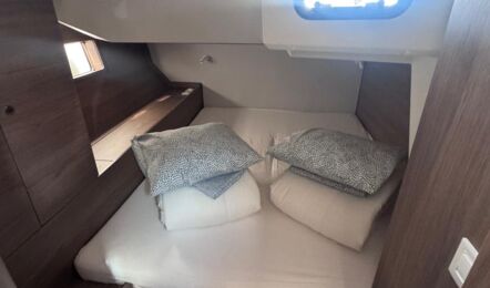 Gästekabine mit Doppelbett und Bullauge einer Oceanis 52 – Yachtcharter in Kroatien