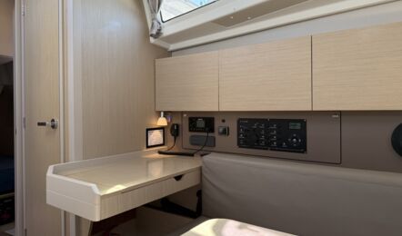 Navigationsecke der Segelyacht Oceanis 38.1 „Nature“ mit Kartentisch, Sitzbereich, Hauptschaltpanel und Radio – Yachtcharter Ostsee