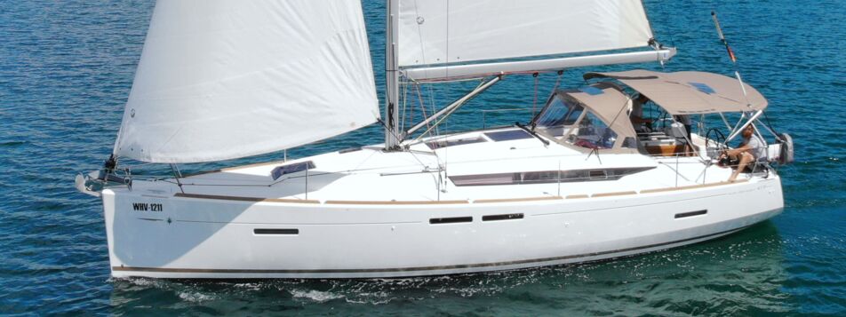 Seitenansicht der Segelyacht Sun Odyssey 419 „Happy Welcome" unter vollen Segeln mit Bimini vor Punat – Yachtcharter Kroatien