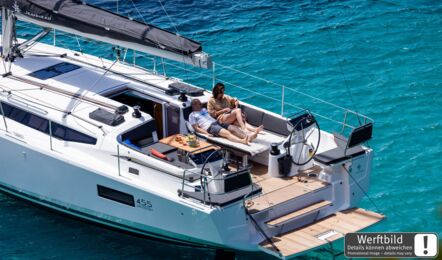 Cockpit einer Sun Odyssey 455 mit zwei Steuerständen sowie Mann und Frau auf der erweiterten Liegefläche mit herabgelassenem Cockpittisch (Werftbild) – Yachtcharter Kroatien