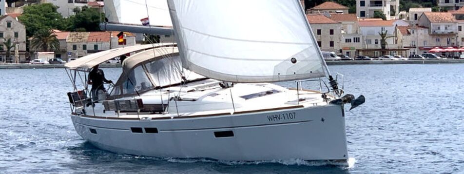 Segelyacht Sun Odyssey 479 „Anna“ in Profilansicht unter Segeln vor einem Küstenort bei Rogoznica – Yachtcharter Kroatien