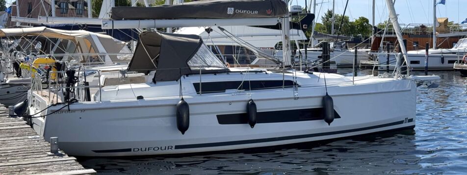 Steuerbordansicht der Segelyacht Dufour 37 „Chiquitita“ mit Sprayhood am Steg in Heiligenhafen – Yachtcharter Ostsee