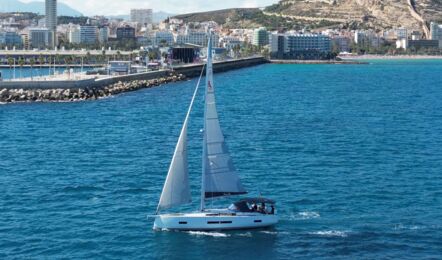 Die Segelyacht Hanse 460 „Antares“ unter Segeln vor der Skyline einer Küstenstadt – Yachtcharter Mallorca