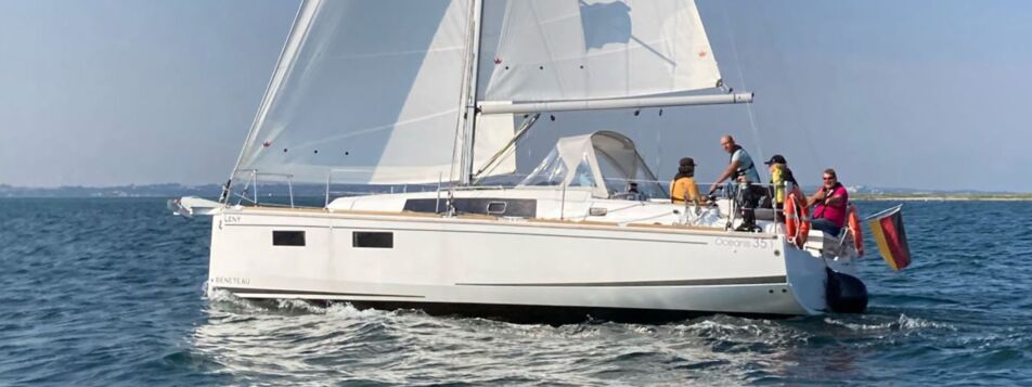 Die Segelyacht Oceanis 35.1 „Leny“ unter vollen Segeln mit Crew im Cockpit auf der Ostsee – Yachtcharter Heiligenhafen
