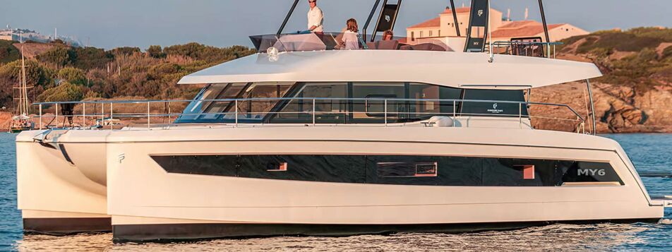Motorkatamaran Fountaine Pajot MY6 mit Flybridge bei Sonnenuntergang vor der Küste (Werftbild) – Yachtcharter Mallorca