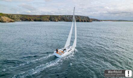 Heck- und Deckansicht einer Oceanis 37.1 unter Segeln vor einer Küste mit Klippen aus der Vogelperspektive (Werftbild) – Yachtcharter Ostsee