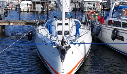 Frontale Bugansicht der Segelyacht Sun Fast 3300 „JFF One“ mit oranger Zierlinie im Hafen Heiligenhafen – Yachtcharter Ostsee
