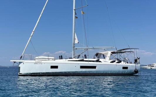 Backbordansicht der Segelyacht Oceanis 51.1.3 „Marny“ vor Anker in azurblauem Wasser mit Küste im Hintergrund – Yachtcharter Kroatien
