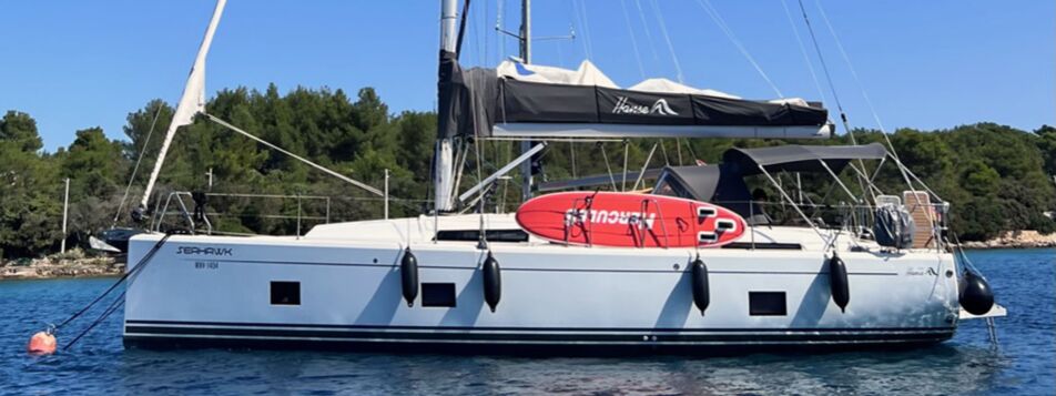 Seitliche Ansicht der Segelyacht Hanse 418 „seahawk“ mit Bimini am Mooring vor bewaldeter Küste – Yachtcharter Kroatien