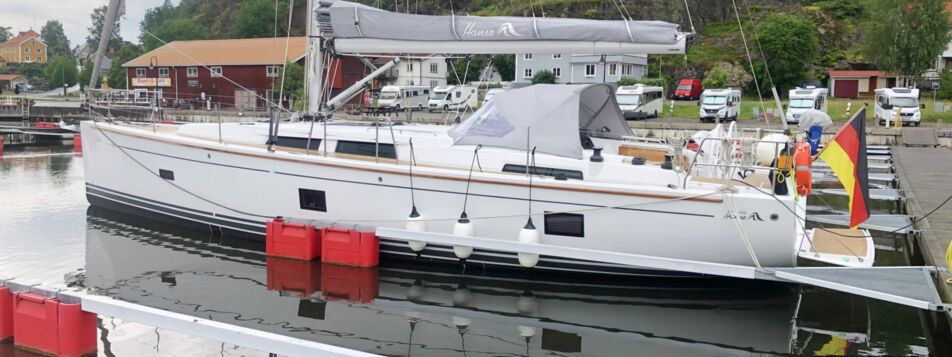 Seitenansicht der Segelyacht Hanse 458 „Willi“ längsseits am Steg vor grüner Küste – Yachtcharter Ostsee ab Heiligenhafen