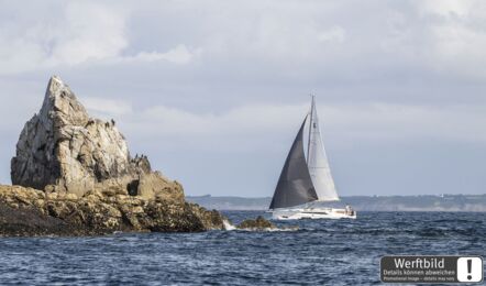 Backbordansicht einer Oceanis 37.1 unter Segeln mit Felsen im Vordergrund und Küste im Hintergrund (Werftbild) – Yachtcharter Ostsee