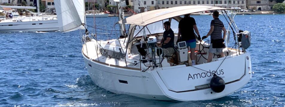 Heckansicht der Sun Odyssey 389 „Amadeus“ mit Crew im Cockpit unter Bimini beim Segeln vor der kroatischen Küste – Yachtcharter Kroatien