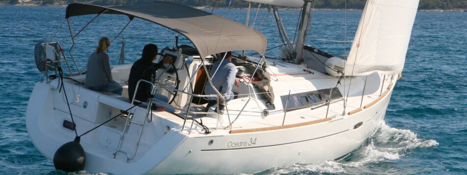 Achteransicht der Segelyacht Oceanis 34.2 „LL Skyhawk" mit Bimini und Crew unter Segeln – Yachtcharter Kroatien