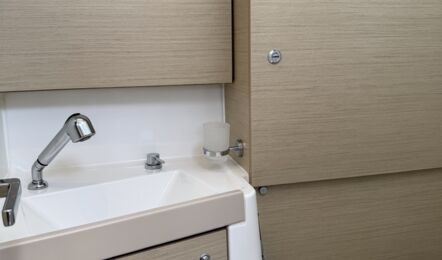 Badezimmer auf der Steuerbordseite der Segelyacht Oceanis 38.1 „Nature“ mit hellem Holzausbau, WC und Spüle – Yachtcharter Ostsee
